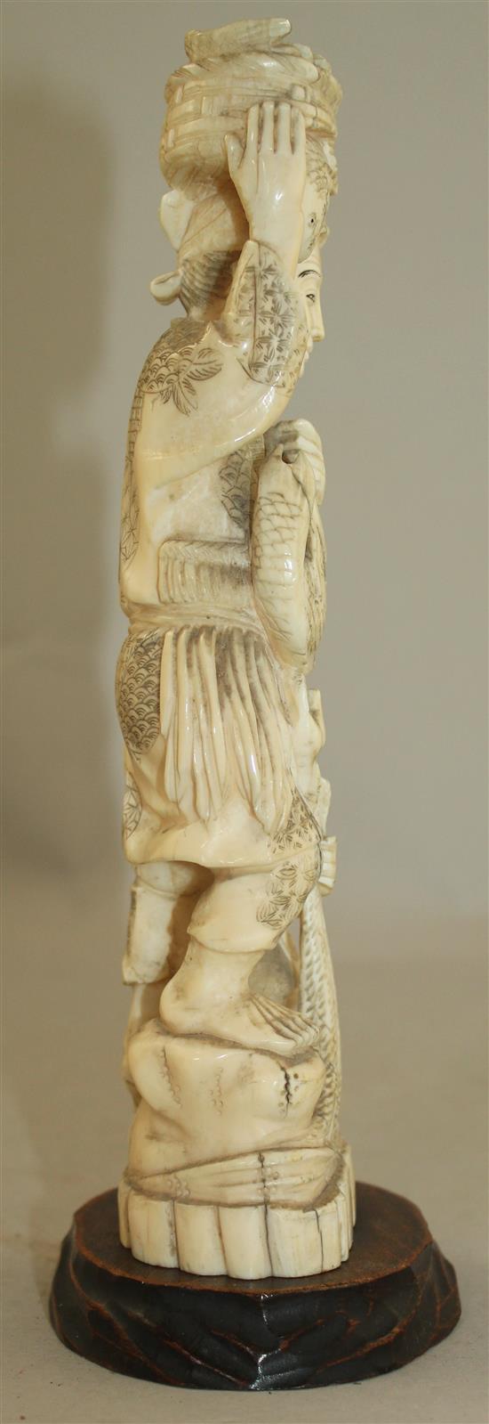 A Japanese walrus ivory group of a fisherman and a boy, early 20th century 21.5cm, wood stand